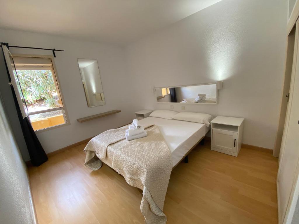 a bedroom with a bed and a table and a window at Las Lomas - Apartamentos in Costa Calma