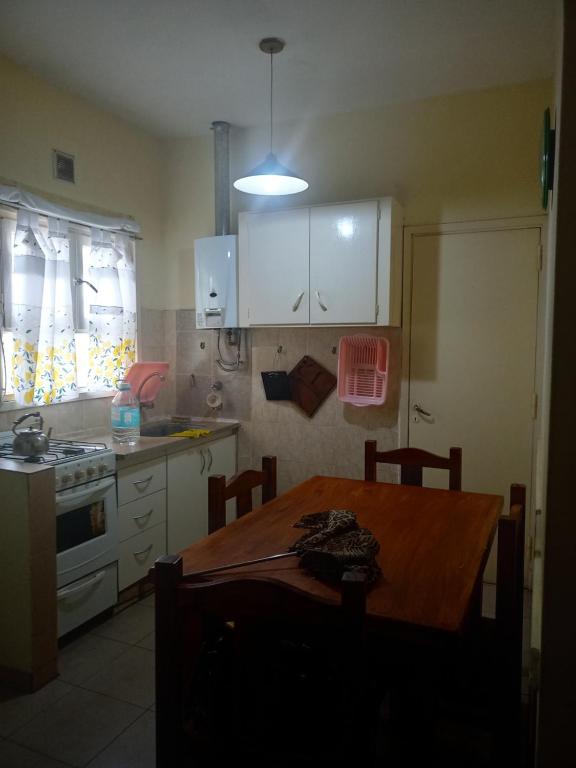 una cocina con mesa de madera y una cocina con armarios blancos. en Departamento 4 ambientes para 5 personas 1 cama doble y una cucheta de 3 en Mar del Plata