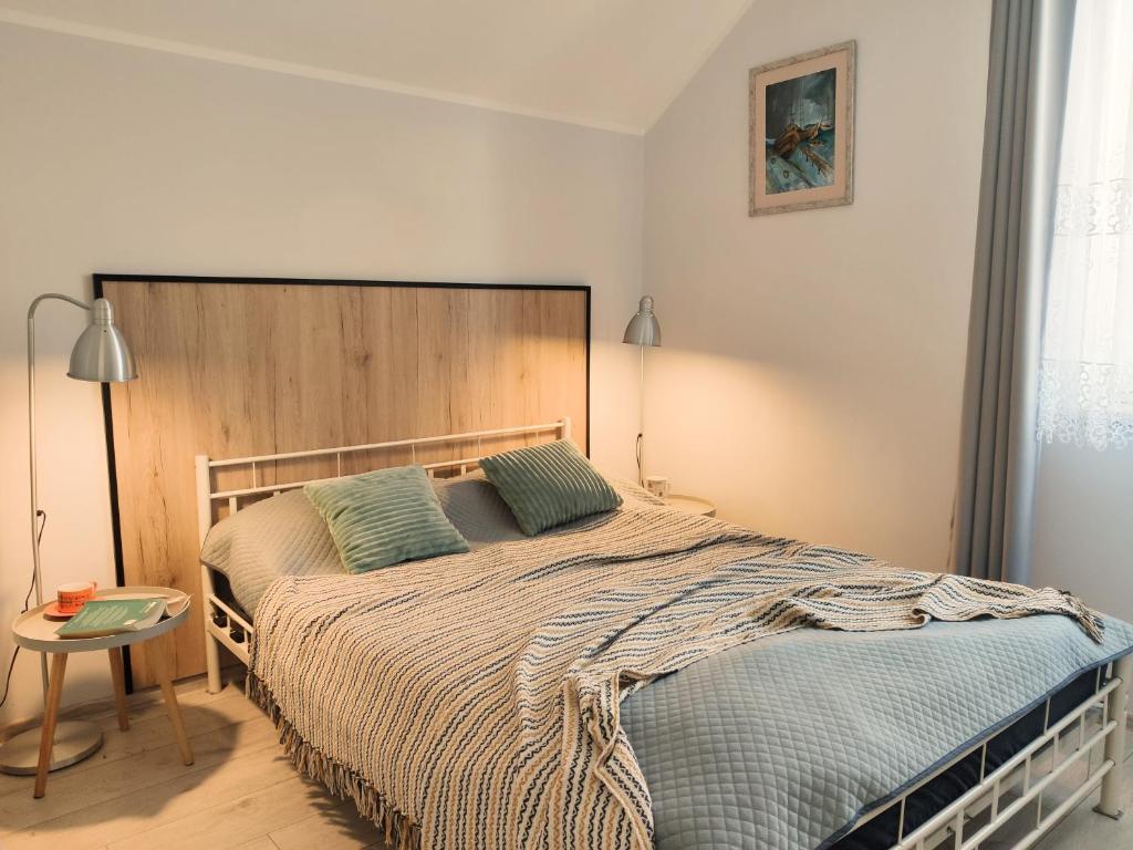 a bedroom with a large bed with a wooden headboard at HOSTE Apartamenty na wczasy in Chmielno