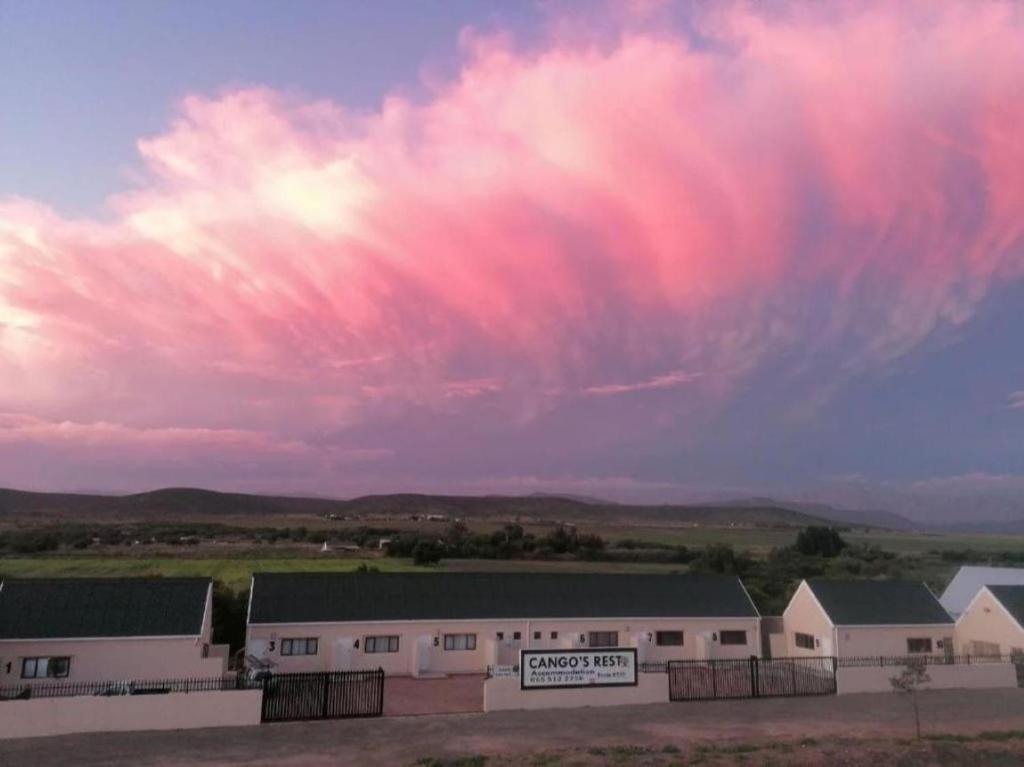 a pink cloud in the sky over a building at Cango's Rest in Oudtshoorn