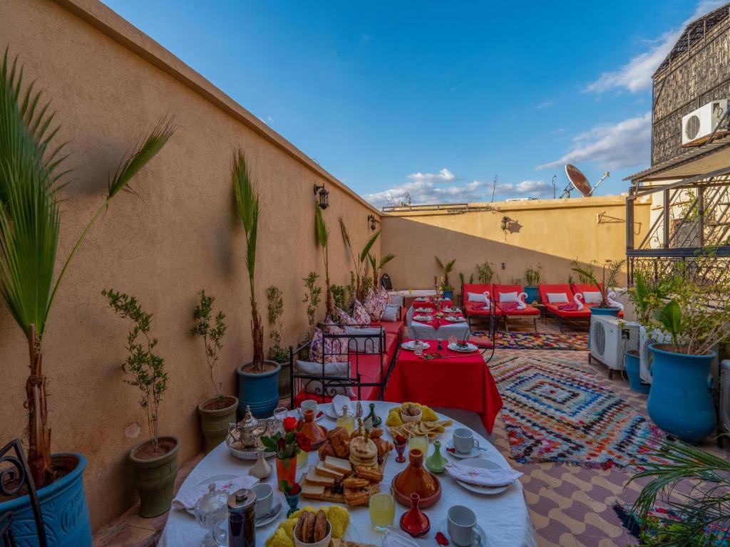 a patio with tables and chairs with food on it at Riad des remparts Marrakech in Marrakesh