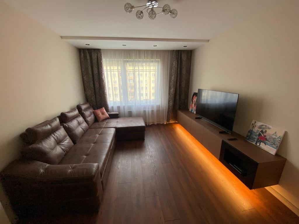 sala de estar con sofá de cuero y TV de pantalla plana en BLUE SKY APARTMENT, en Jūrmala