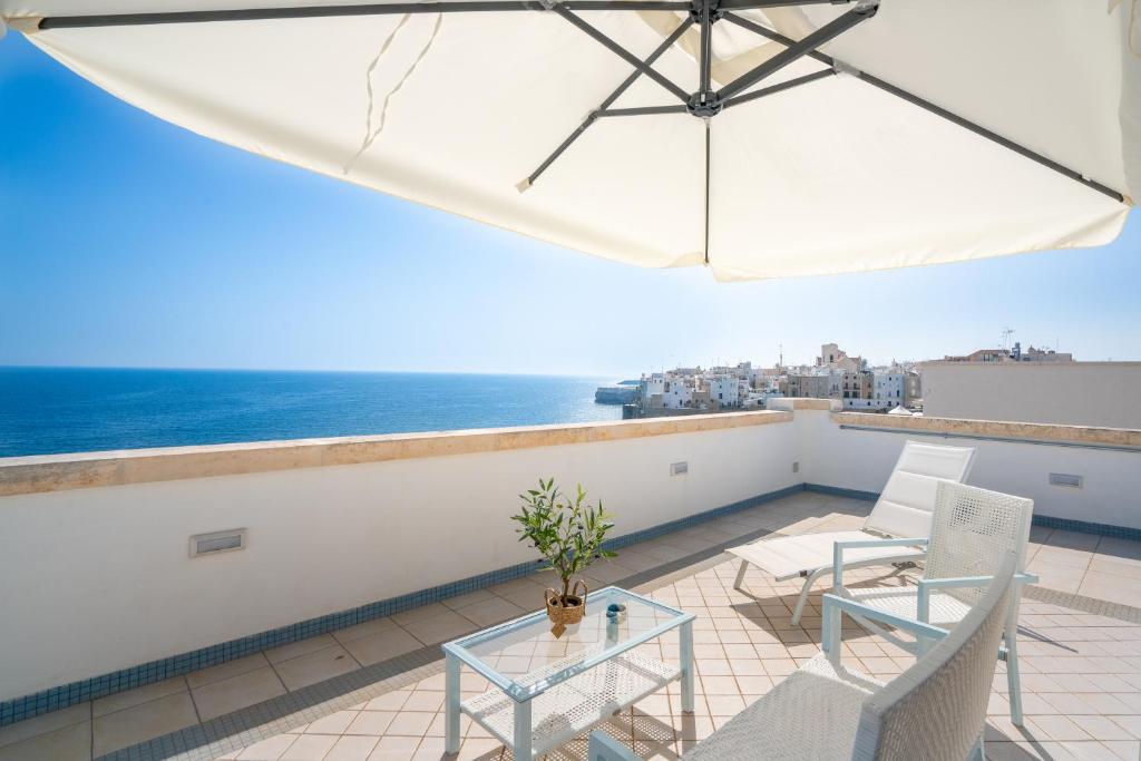 a balcony with a table and chairs and an umbrella at Donnamaria - Dimora Vista Mare in Polignano a Mare