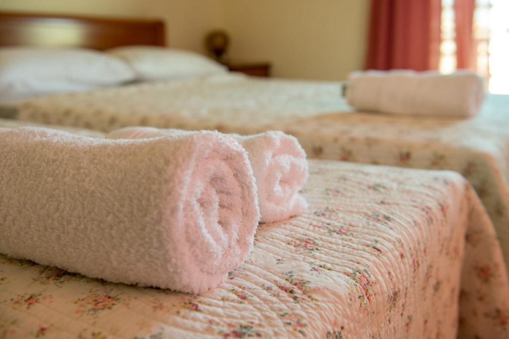 dwa łóżka z różowymi ręcznikami na górze w obiekcie Polymnia Studios w mieście Olympiakí Aktí