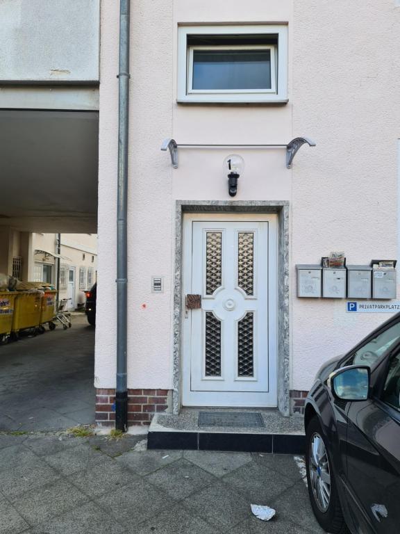 una puerta blanca en un edificio con un coche aparcado delante en TS1 2-OG Möbilierte Wohnung in Wolfsburgs Zentrum, en Wolfsburg