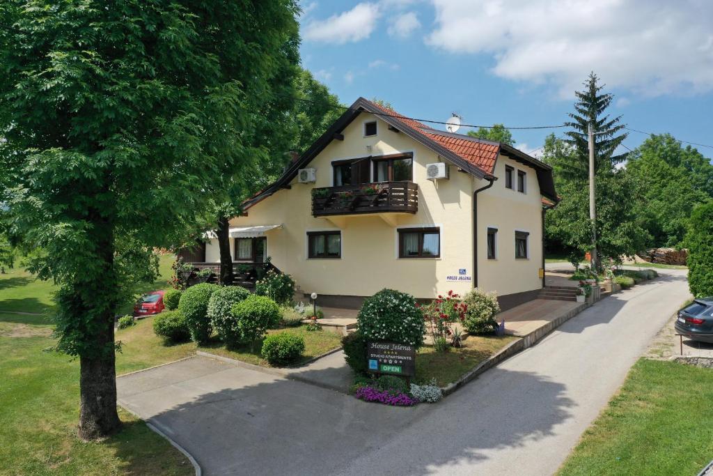 a white house with a tree and a driveway at House Jelena in Seliste Dreznicko