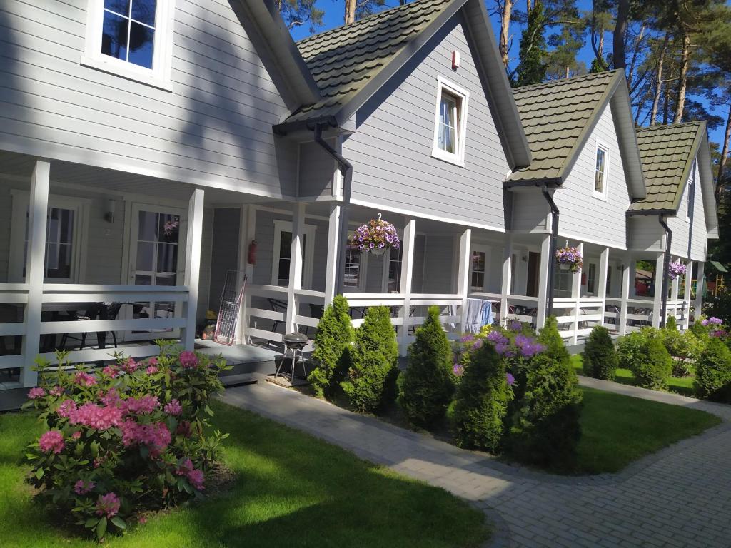 a house with a porch and flowers in the yard at Domki letniskowe in Pobierowo