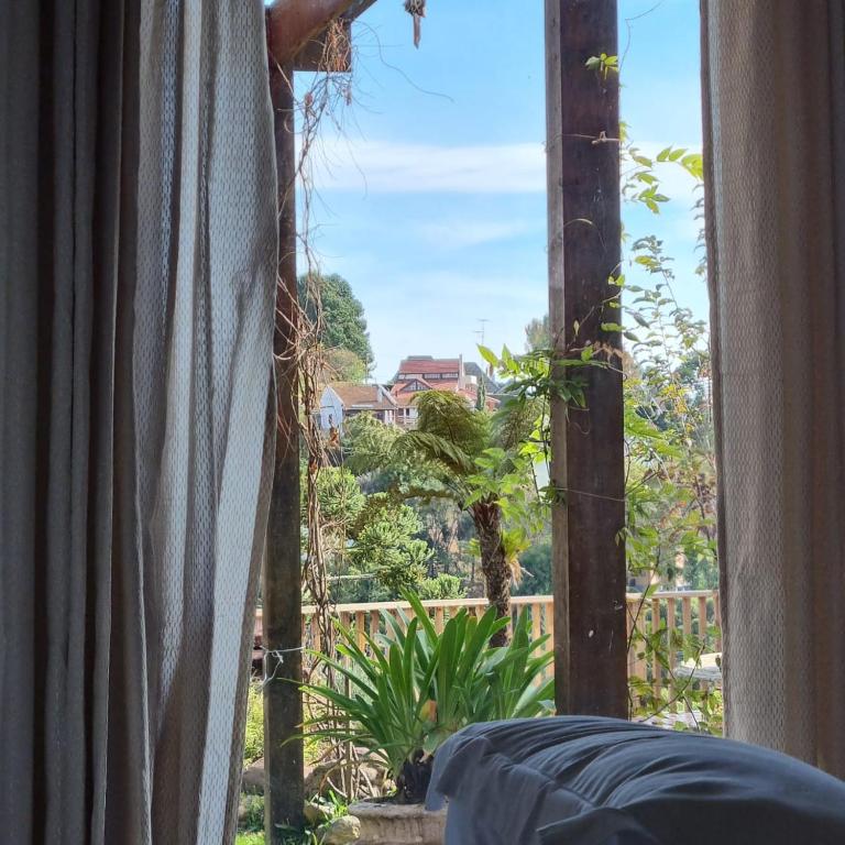 an open window with a view of a garden at Recanto dos Moinhos - Boutique Hotel in Campos do Jordão