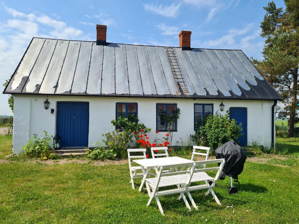 ein weißes Haus mit einem Tisch und Stühlen davor in der Unterkunft Villa Vemmentorp - Körsbärsblomsvillan 6 min från havet in Skurup