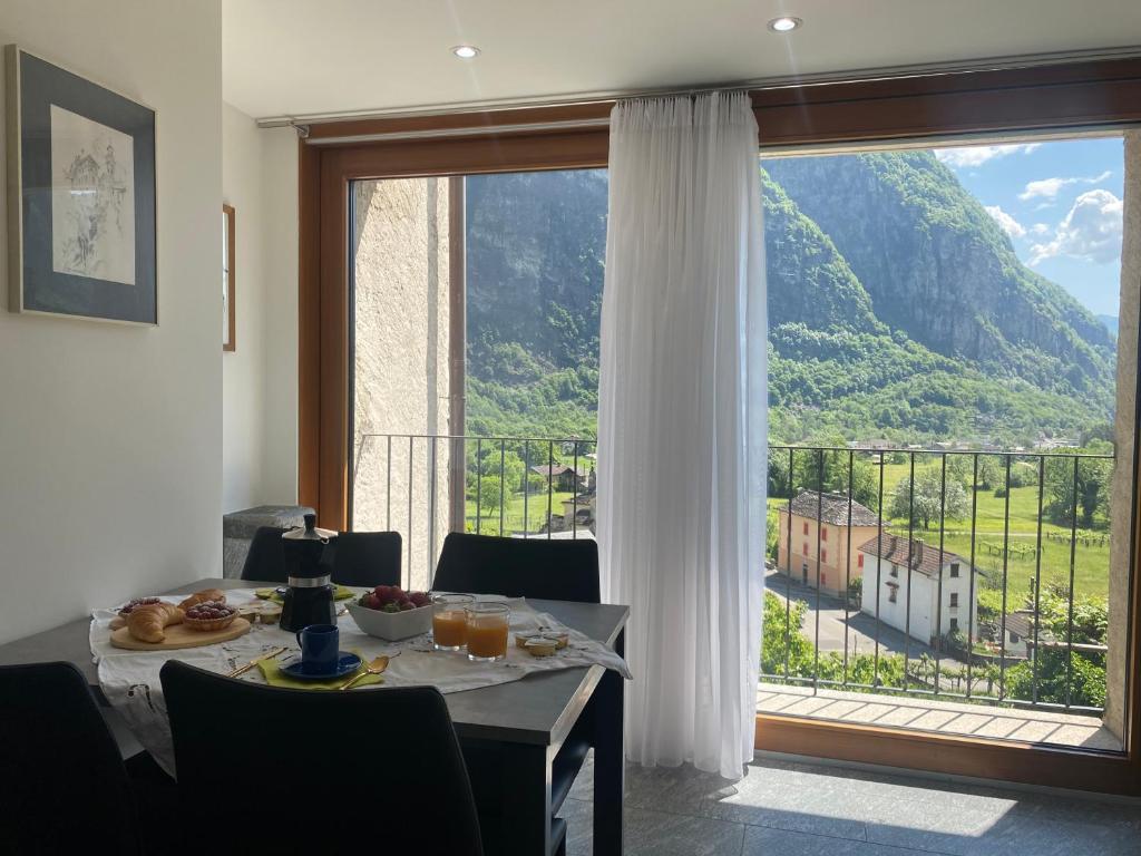 a dining room with a table and a large window at Casa Lele - Sole in Cevio