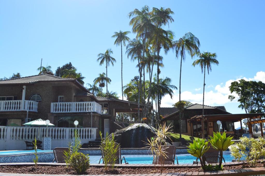 a house with a swimming pool and palm trees at Pousada Terê Parque in Teresópolis