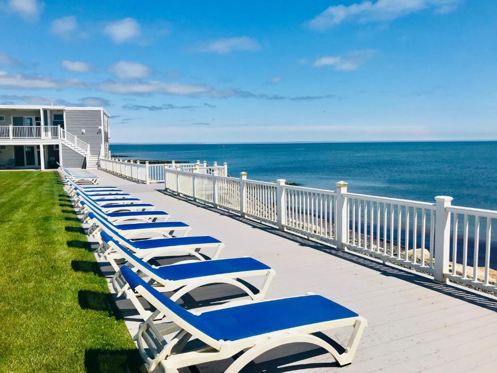 a row of chaise lounges on a balcony overlooking the ocean at The Garlands Motel in Dennis Port