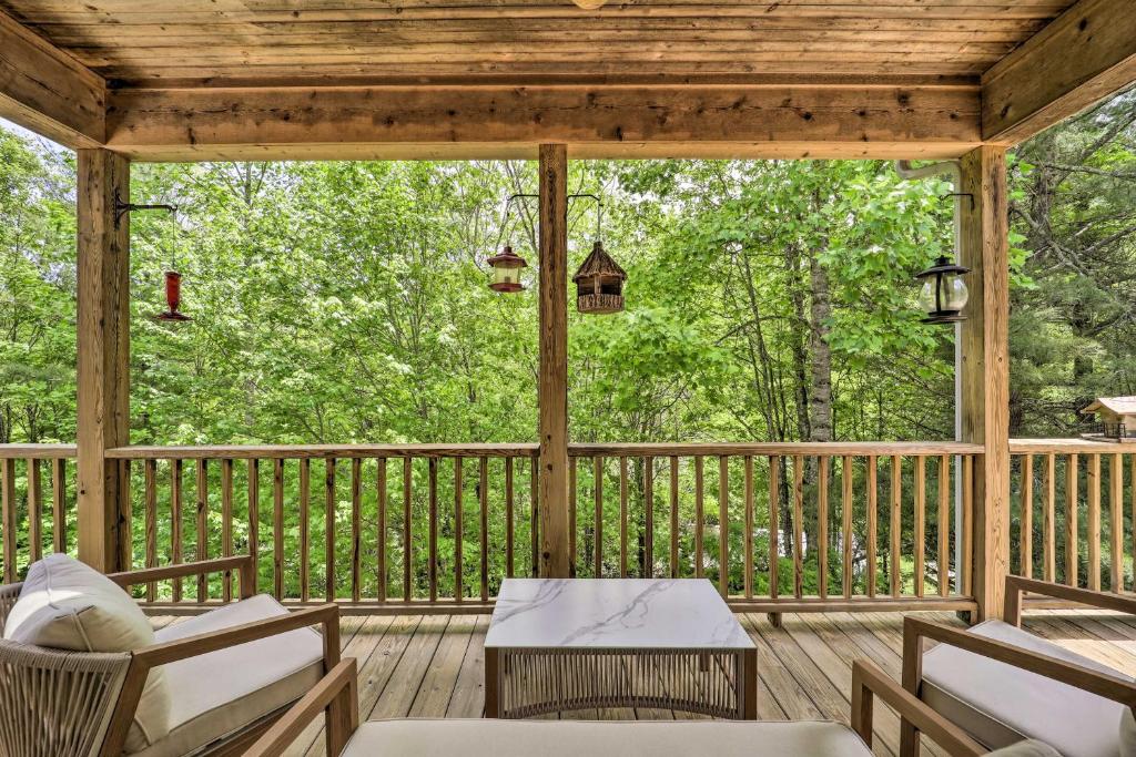 un porche cubierto con sillas y mesa en Blue Ridge Mountain Sanctuary with Pond and Views!, en Banner Elk