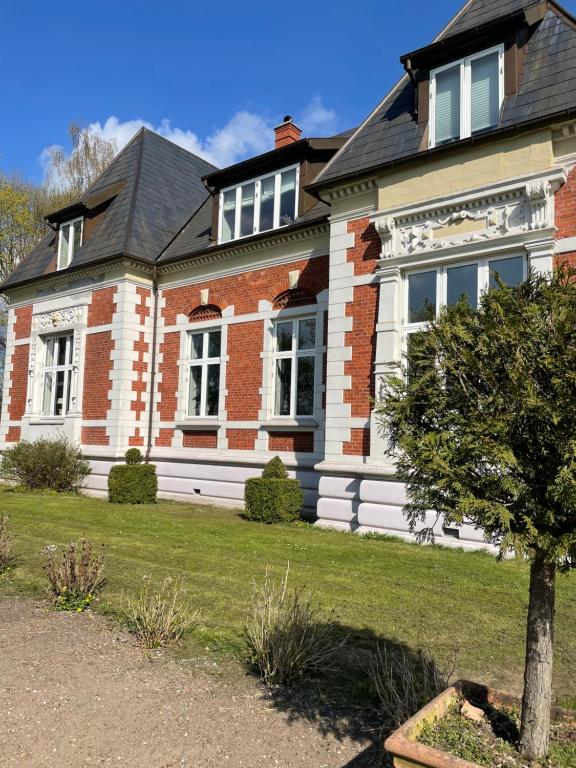 una casa di mattoni con un albero di fronte di Dobbeltværelse i smuk palævilla a Stenstrup