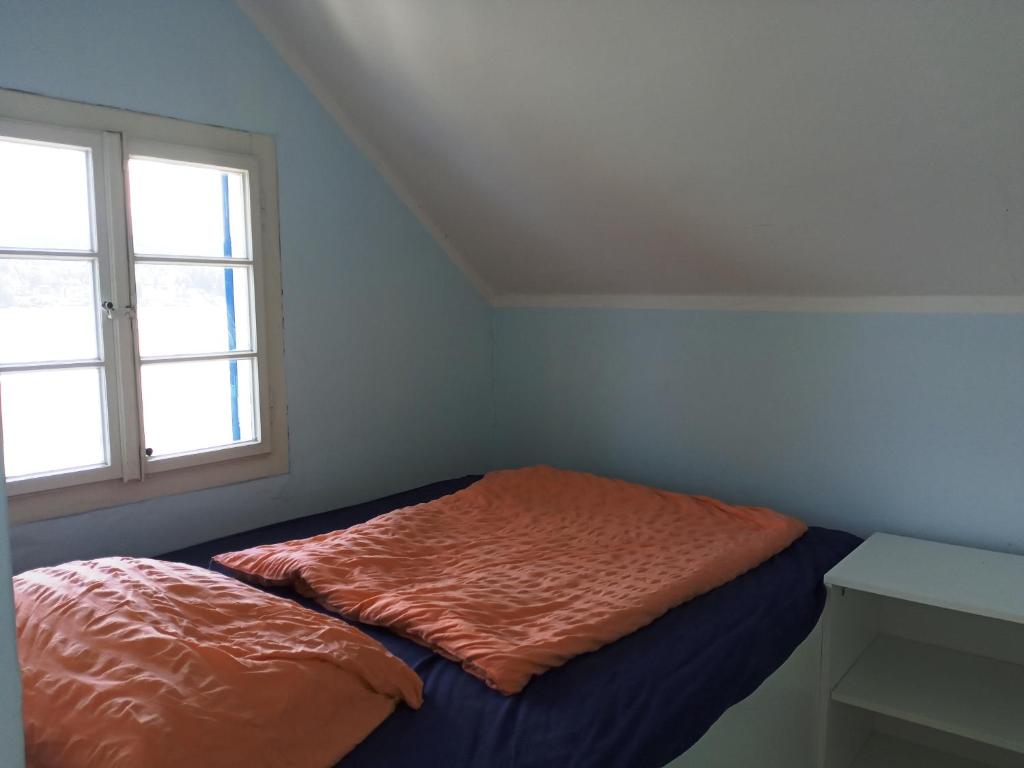 uma cama com um edredão laranja num quarto com uma janela em Seehaus traumhaft Wörthersee em Tiebitsch