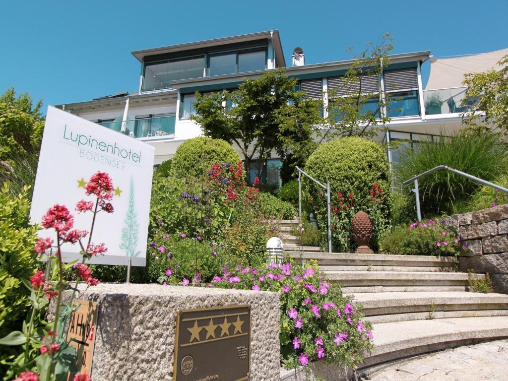 a house with a sign in front of a garden at Lupinenhotel Bodensee in Sipplingen