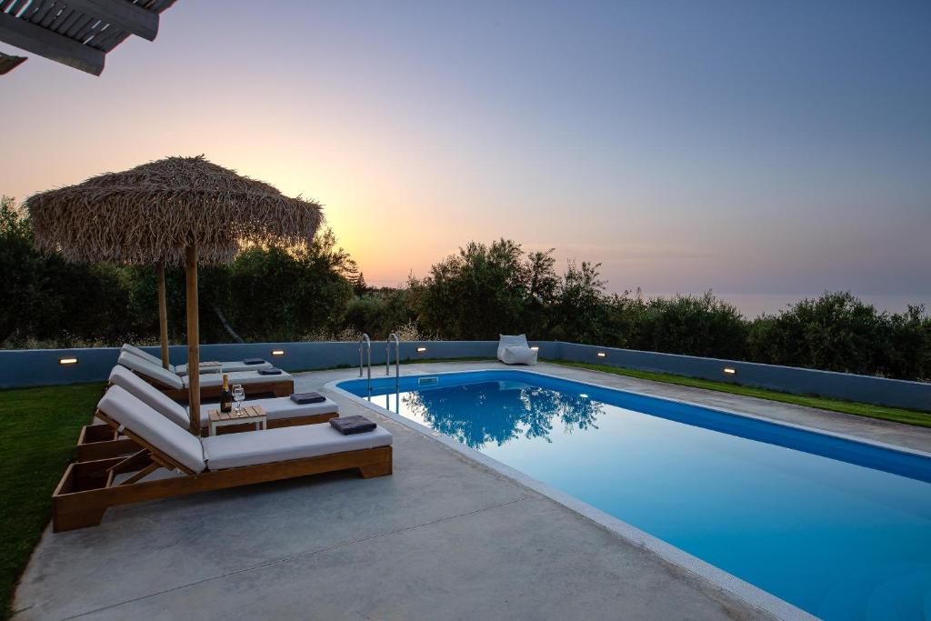 a swimming pool with chairs and an umbrella at Gramvella Resort in Adelianos Kampos