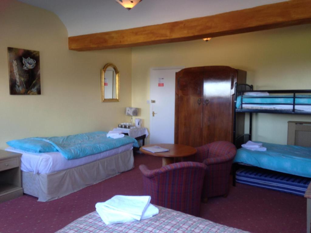 um quarto de hotel com 2 beliches, uma mesa e cadeiras em The Old School B&B em Tebay