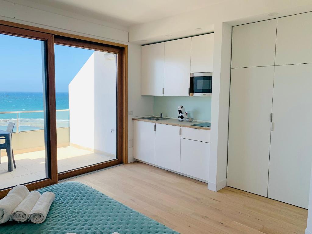uma cozinha com armários brancos e vista para o oceano em Boutique Lungomare em Porto Torres