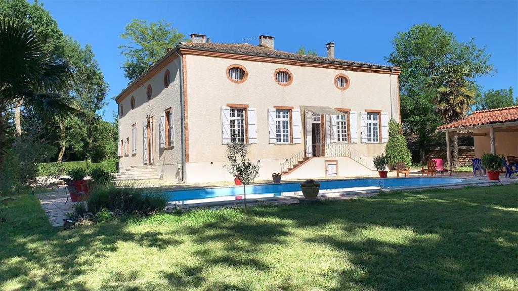une grande maison avec une piscine en face de celle-ci dans l'établissement Manoir de la Gravette Maison d'Hôtes, à Montauban