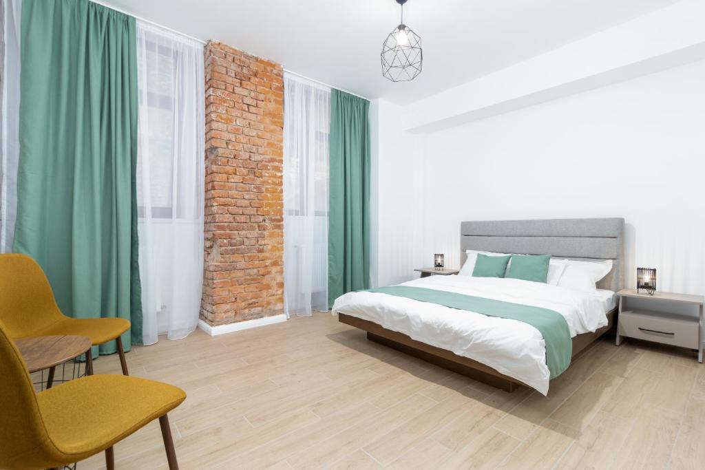 Schlafzimmer mit einem großen Bett und grünen Vorhängen in der Unterkunft CADORO City Center Apartments in Oradea