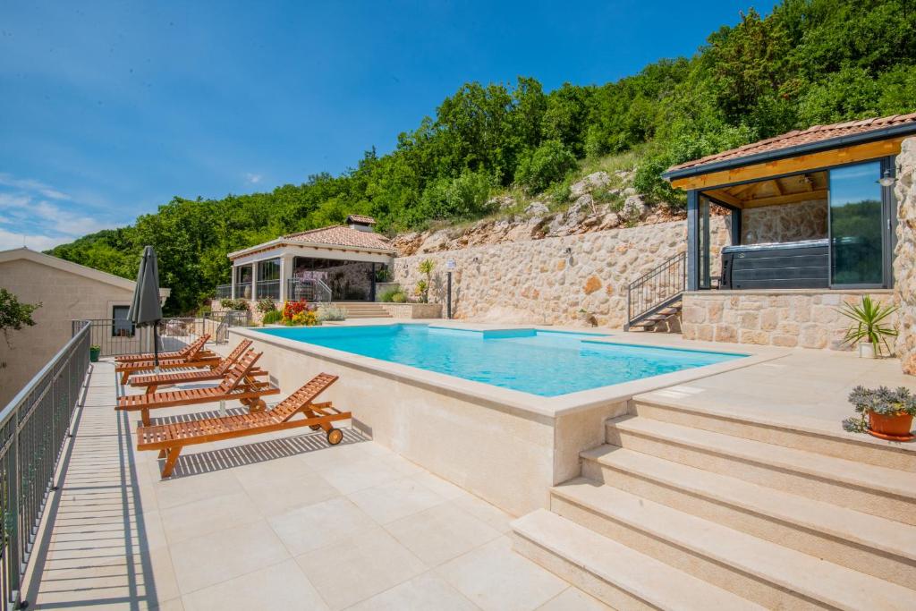 una piscina con bancos y una casa en Luxury Villa Borak, en Imotski