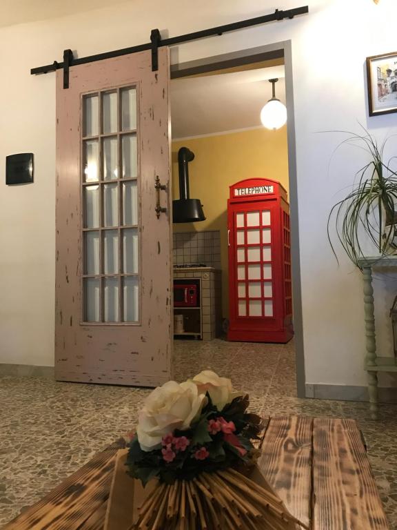 uma cabine telefónica vermelha e um vaso de flores ao lado de uma porta vermelha em Alloggio per turisti a solo 10 minuti dal mare em Monte San Biagio