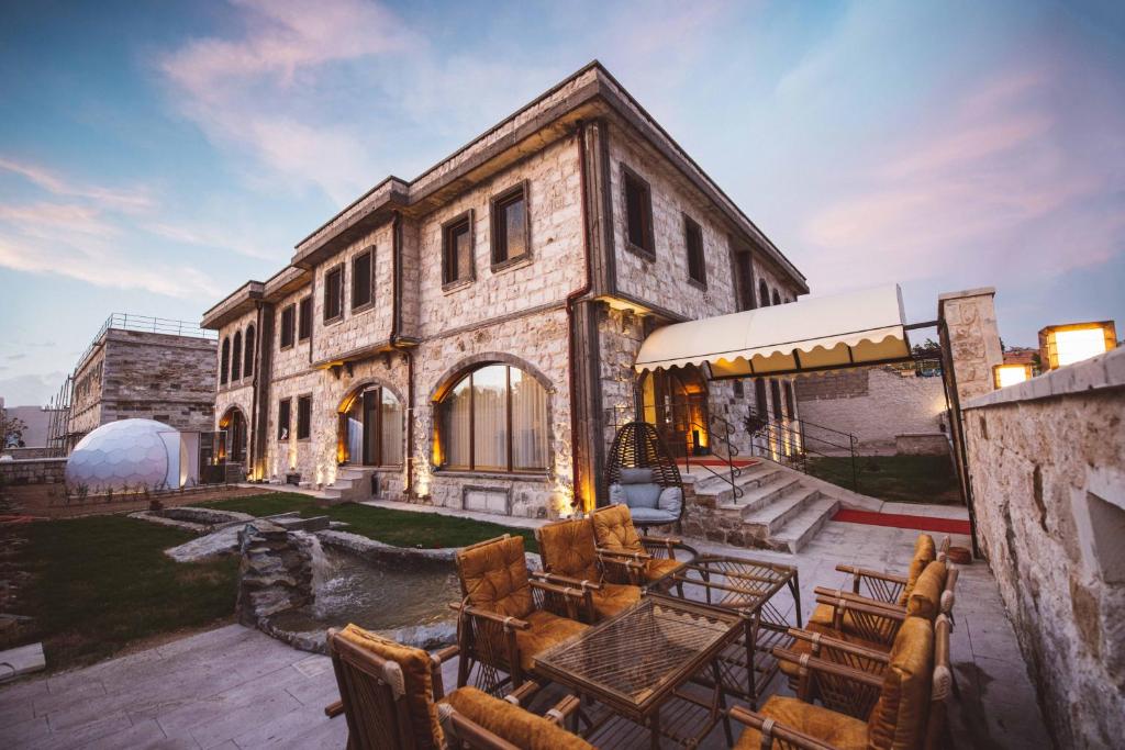 un gran edificio de piedra con mesas y sillas en un patio en Ahiyan Hotel, en Uchisar