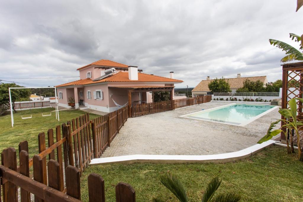 a house with a fence and a swimming pool at Vivenda Esgravina in Sesimbra