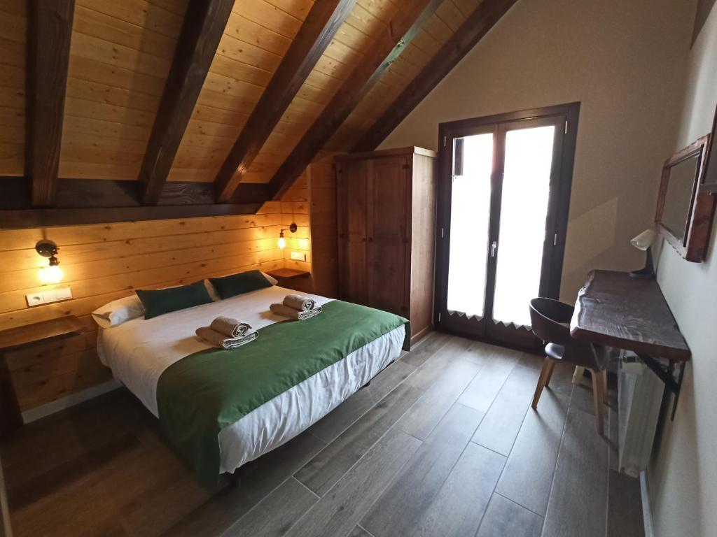 a bedroom with a bed and a desk and a window at Casa rural ELURKOIA in Isaba