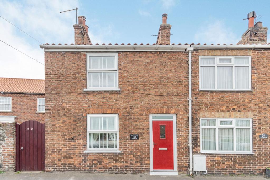 a red brick house with a red door at Fisher Cottage in Hornsea
