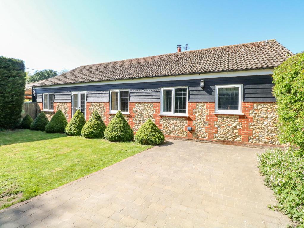 a brick house with a driveway in front of it at The Meadows Cottage in Billingford