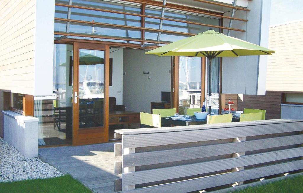 een patio met een tafel met een groene parasol bij Bungalowpark Wijdland-aak in Bunschoten