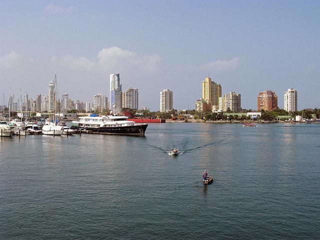 a man rowing a boat in the water near a city at Apartamento en Cartagena, cerca al mar, edificio Nuevo Conquistador in Cartagena de Indias