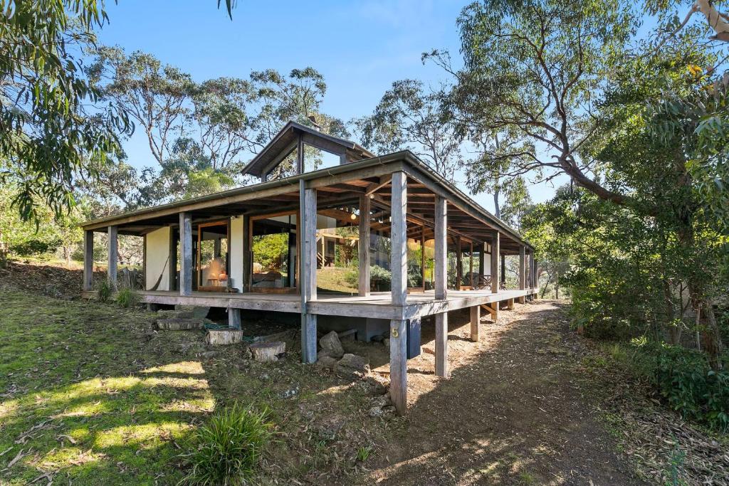 a wooden house with glass windows in a field at Dridan House in Lorne
