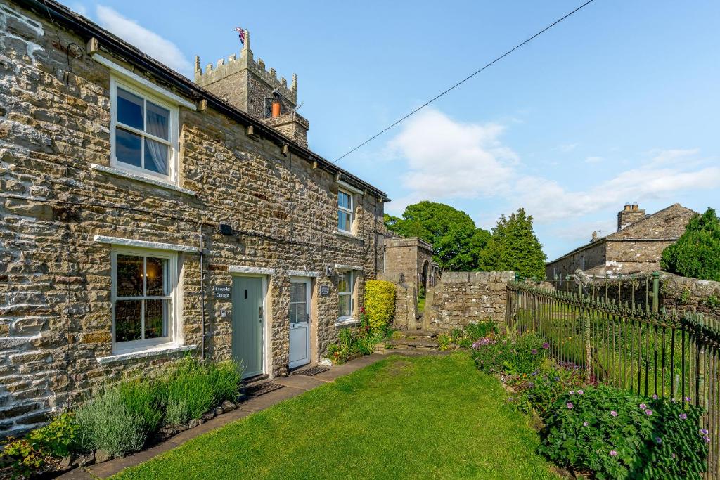 a stone house with a green door and a yard at Lavender Cottage in Askrigg