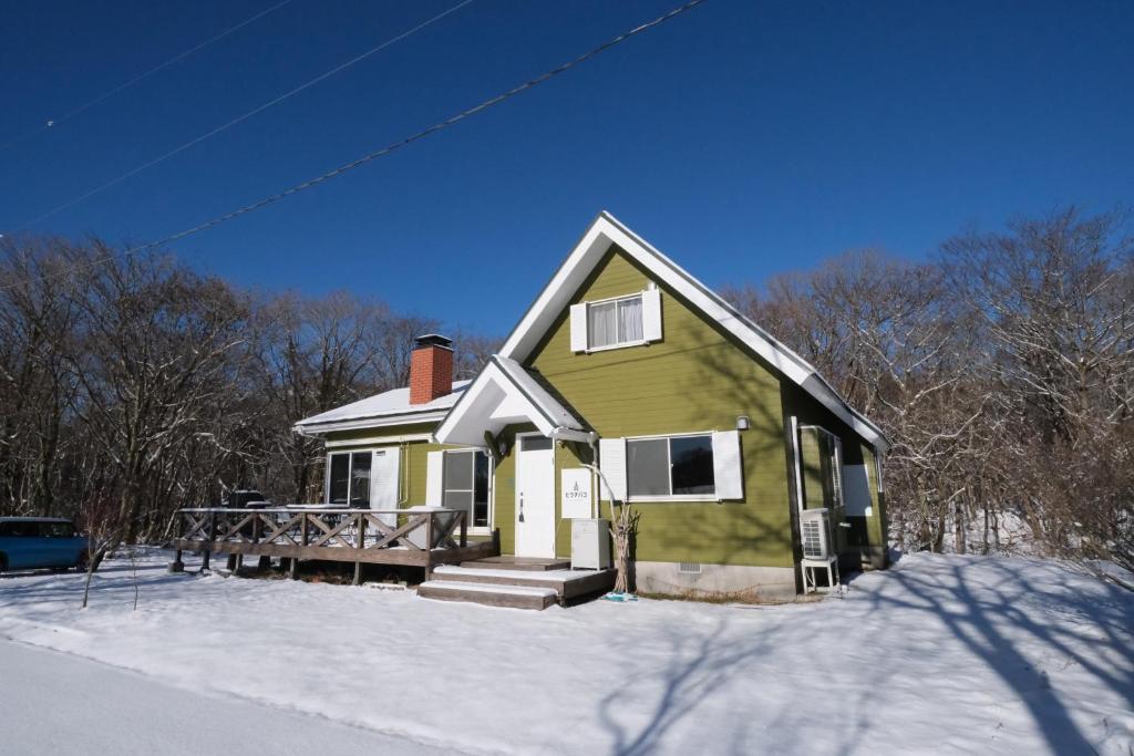 a green and white house in the snow at ヒウチバコ in Fujikawaguchiko