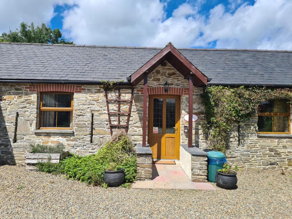 Cabaña de piedra con puerta amarilla en Puffin Cottage, en Whitland