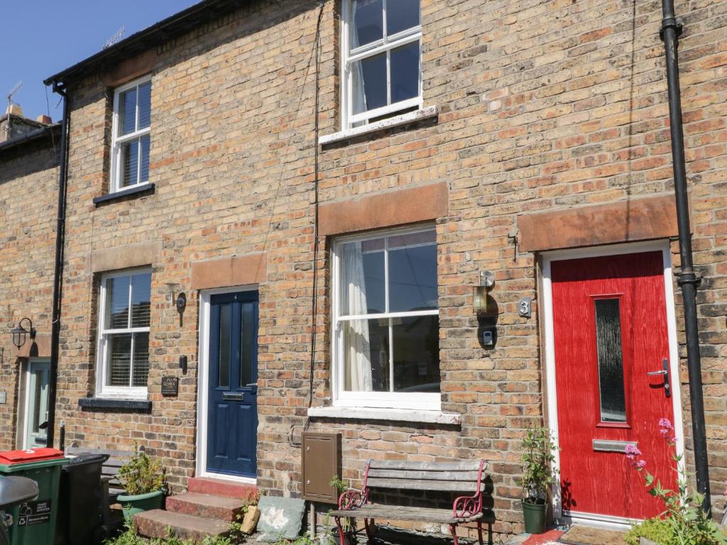 a brick house with a red door and a bench at Banks Place in Keswick