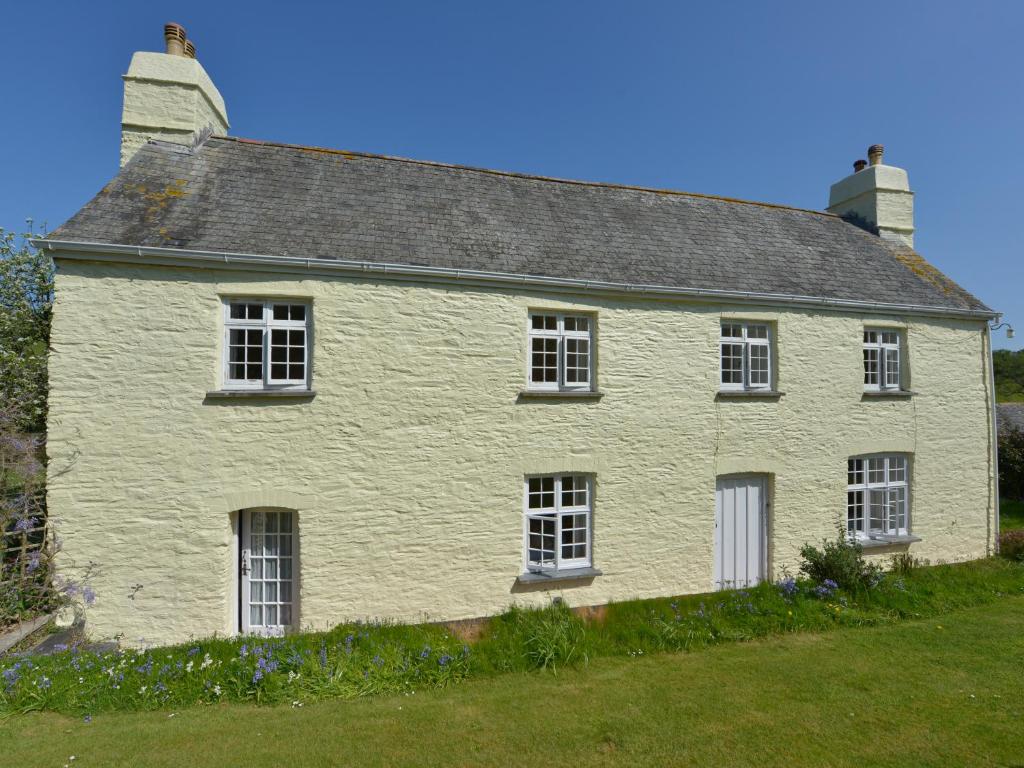 a white house with white windows on a field at Tregonhawke Farmhouse in Cawsand