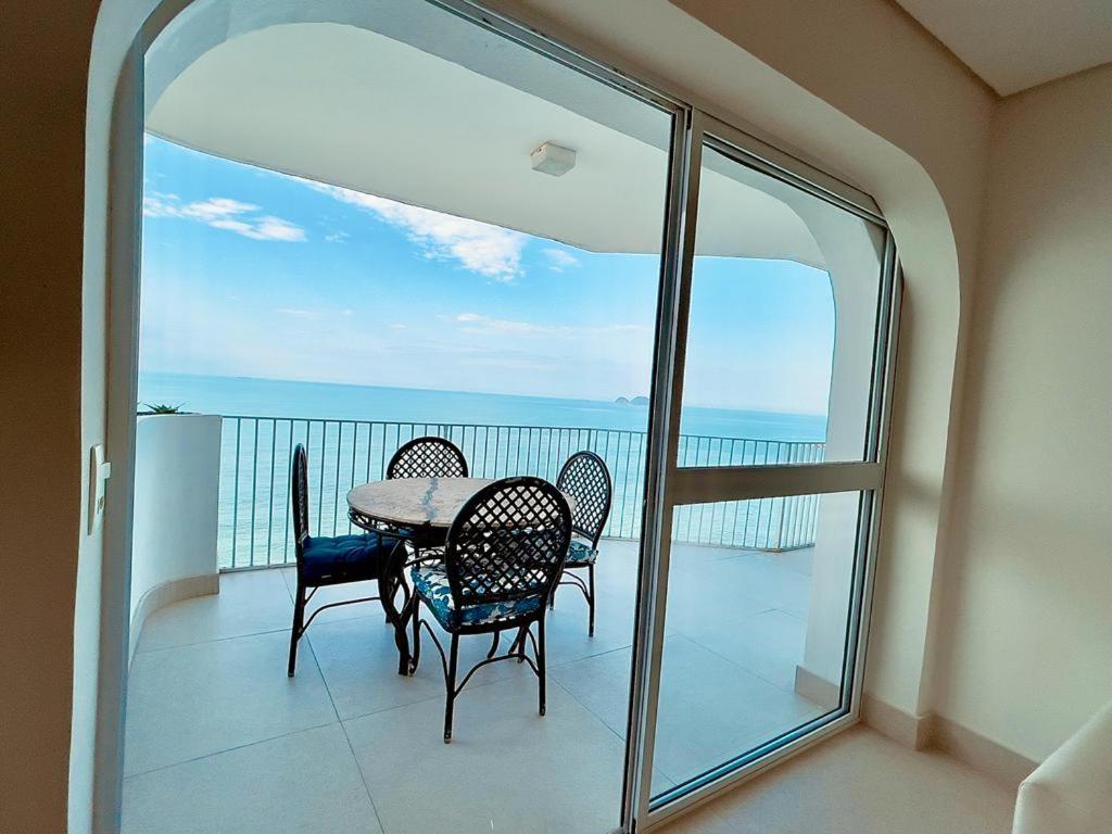 a table and chairs on a balcony with a view of the ocean at Apartamento Guarujá morro do Maluf de frente ao mar! in Guarujá