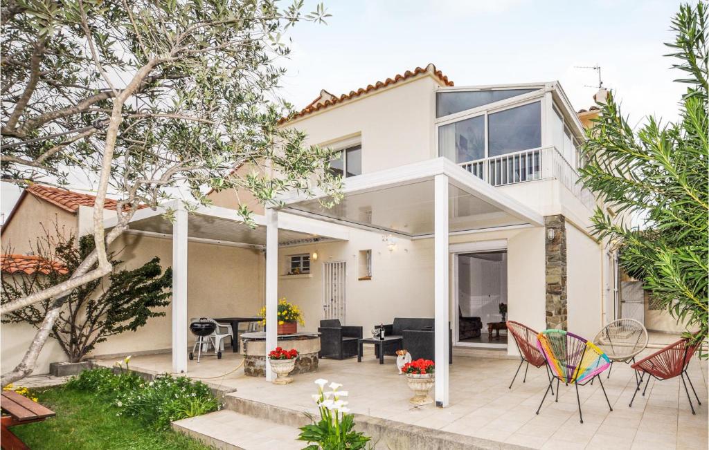 uma casa branca com um pátio e cadeiras em Lovely Home In Argels-sur-mer With Kitchen em Argelès-sur-Mer