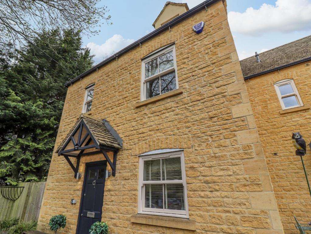 a brick house with a black door and windows at Church View in Bourton on the Water