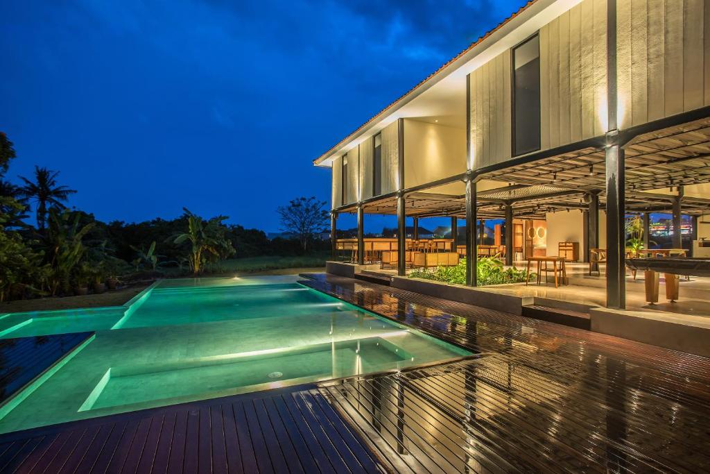 an image of a house with a swimming pool at night at TRIBAL Coworking Bali in Canggu