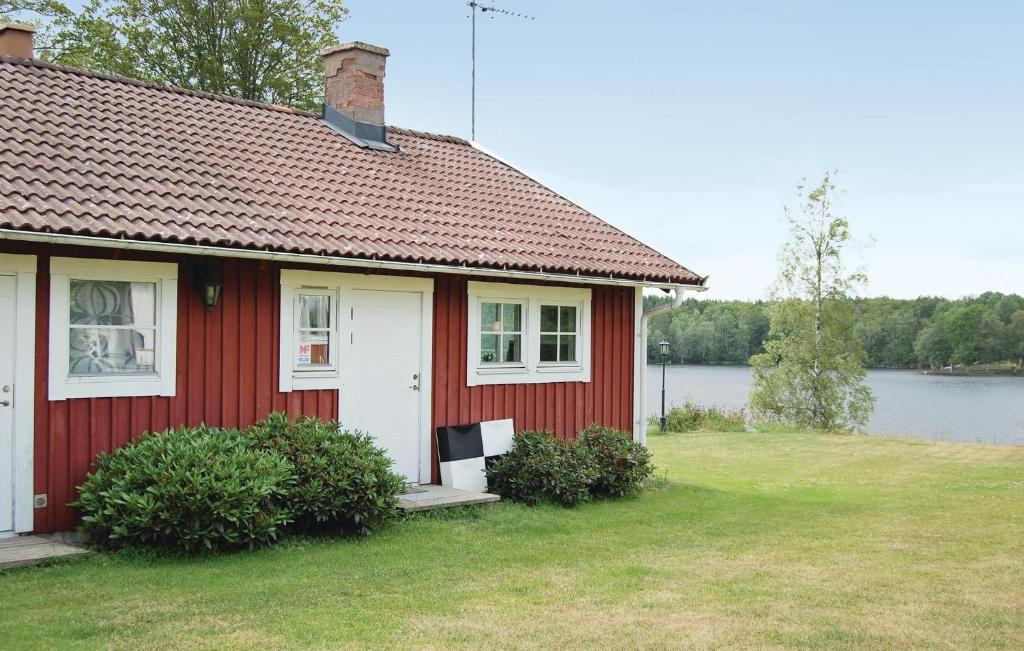 ein rotes Haus mit rotem Dach und einem Wasserkörper in der Unterkunft Cozy Home In Karlskrona With House Sea View in Fröbbestorp