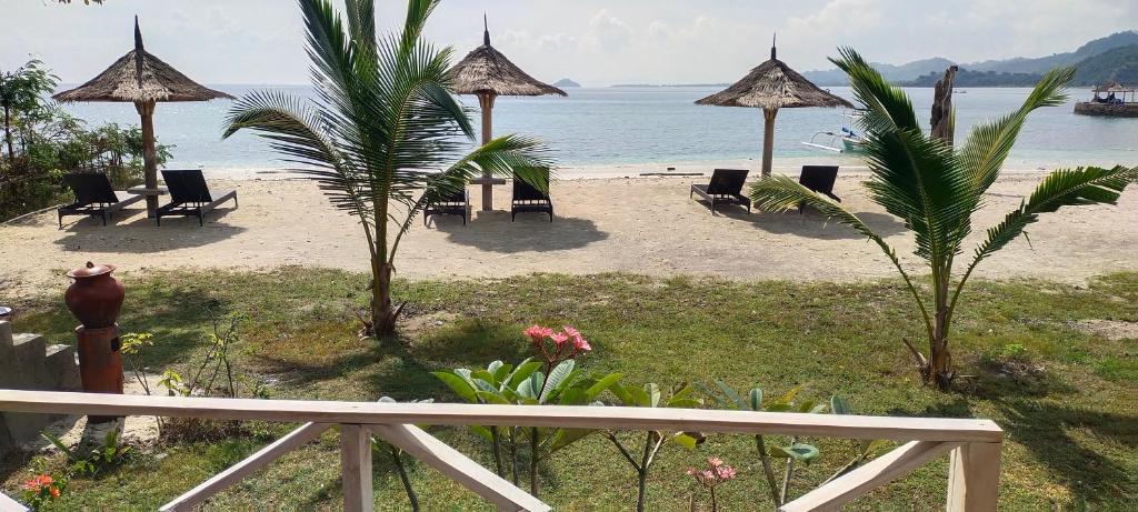 Blick auf einen Strand mit Stühlen und Sonnenschirmen in der Unterkunft Alam Karang in Gili Gede