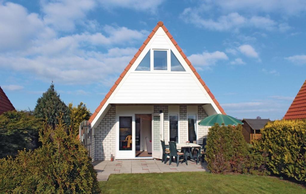 a small white house with a gambrel roof at Bungalow 195 in Den Oever