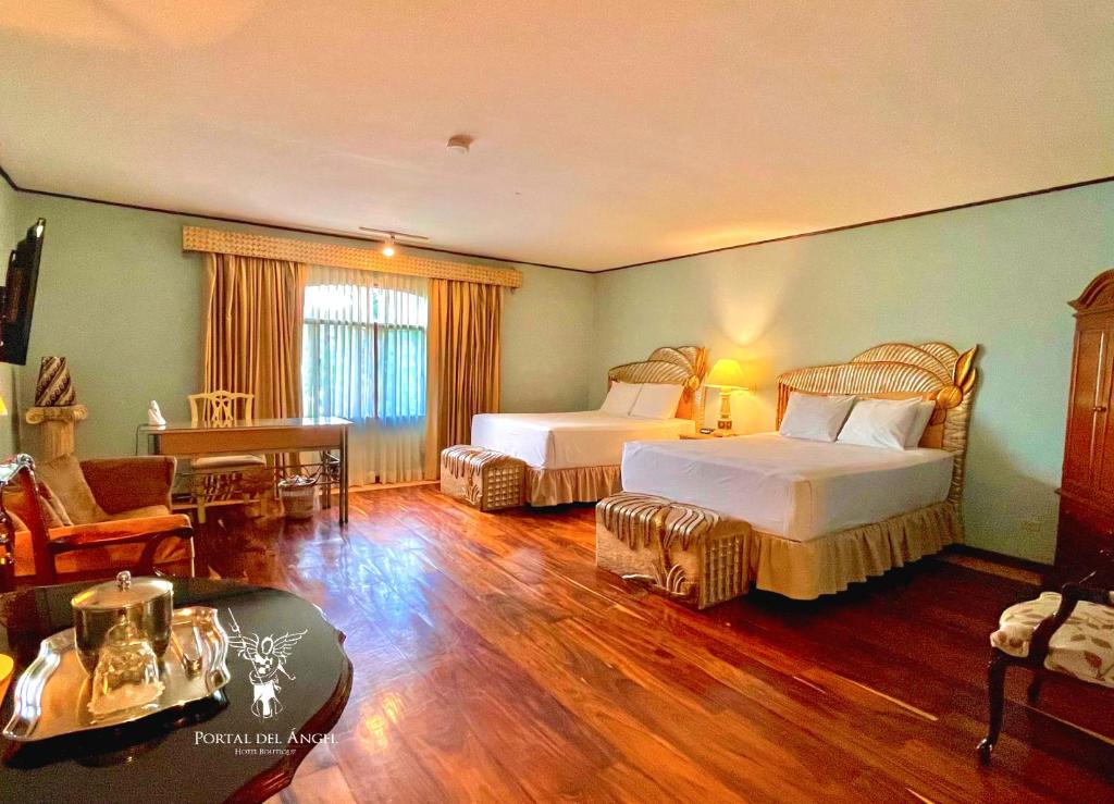 Habitación de hotel con 2 camas y sala de estar. en Hotel Portal del Angel en Tegucigalpa