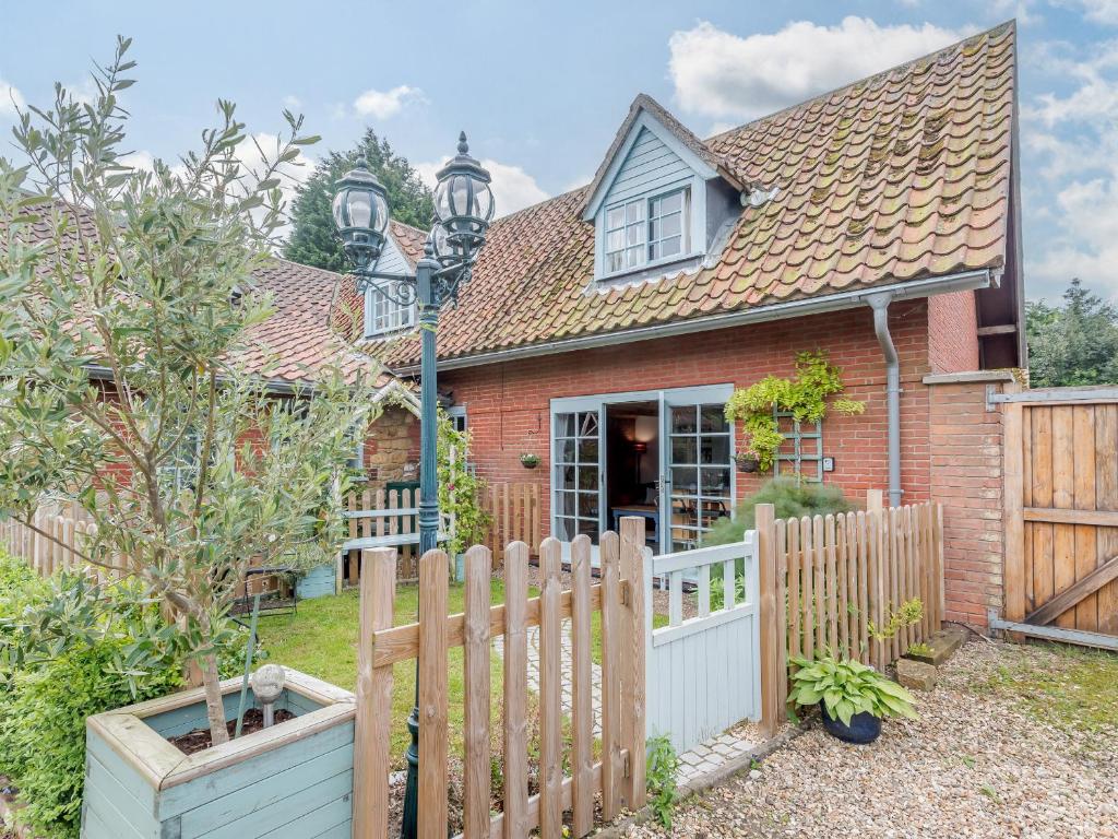 a house with a wooden fence in the yard at Gables Cottage in Market Rasen