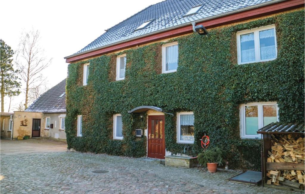 a green ivy covered house with a red door at Cozy Apartment In Marlow Ot Gresenhorst With Kitchen in Gresenhorst